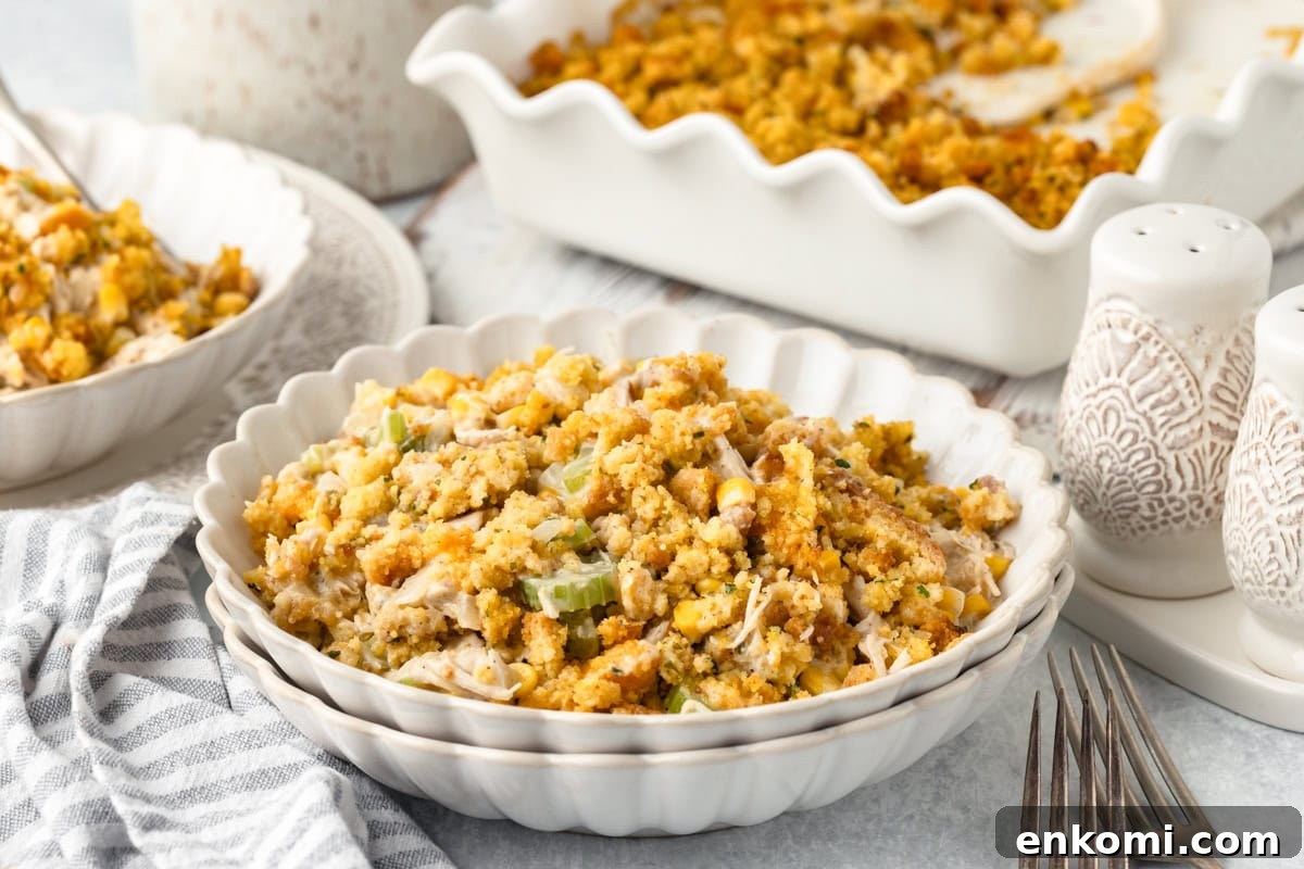 Creamy Chicken and Savory Stuffing Casserole Recipe 6 A bowl of chicken and stuffing casserole sits in front of a baking dish containing more casserole.
