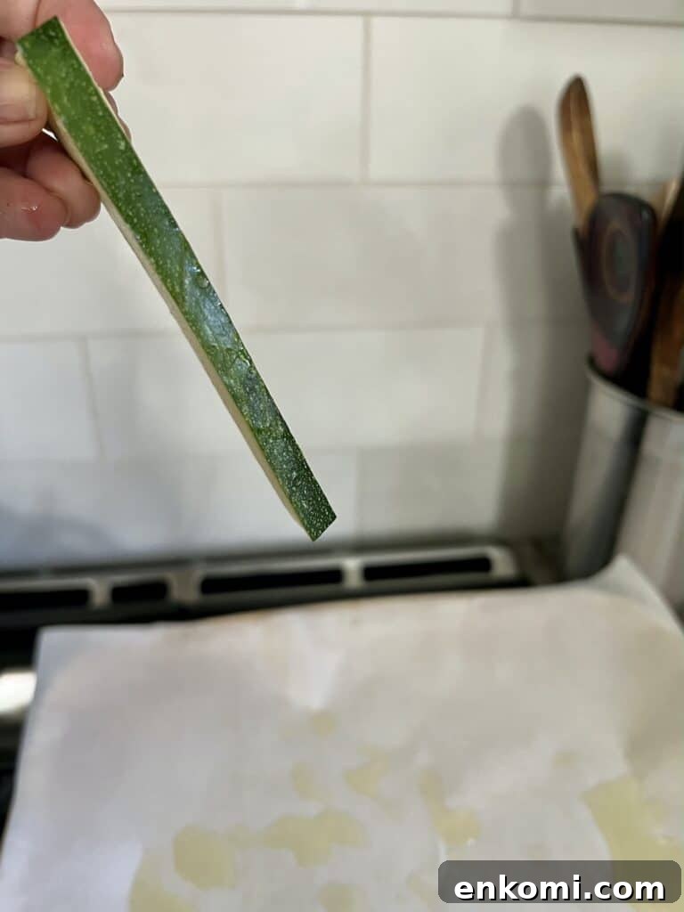 Piece of zucchini showing thickness being help up in hand.