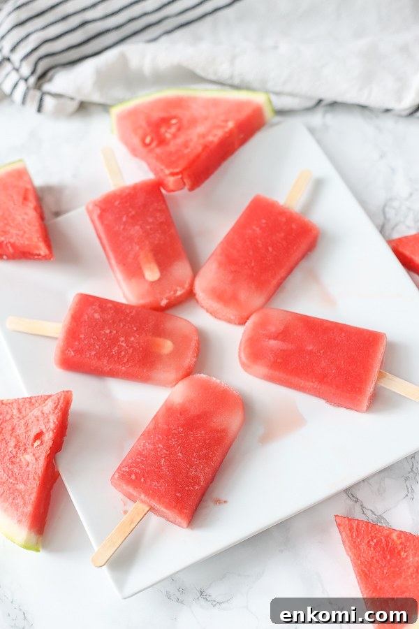 watermelon popsicles on white plate with watermelon slices around it