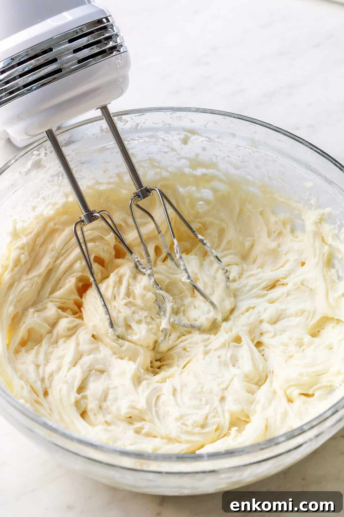 Bowl of cream cheese frosting with hand mixer.