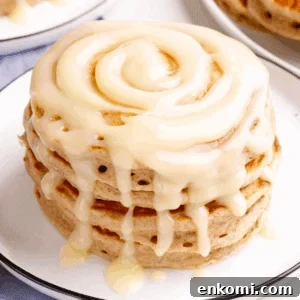 A stack of cinnamon pancakes with cream cheese glaze on a plate.