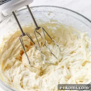 Bowl of cream cheese frosting with hand mixer.