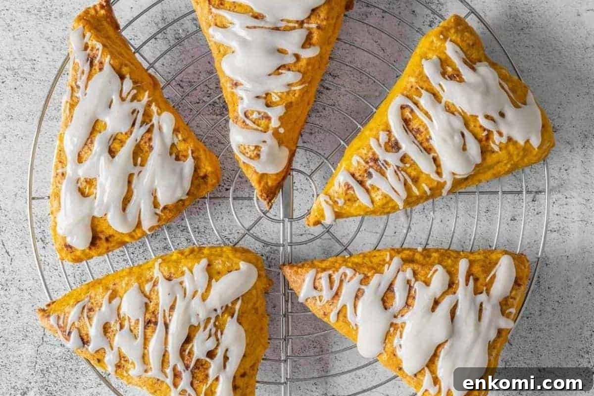 29 Fall Desserts That Bring Generations of Flavor Together 11 Five Pumpkin Spice scones with vanilla glaze arranged in a circle on a cooling rack.