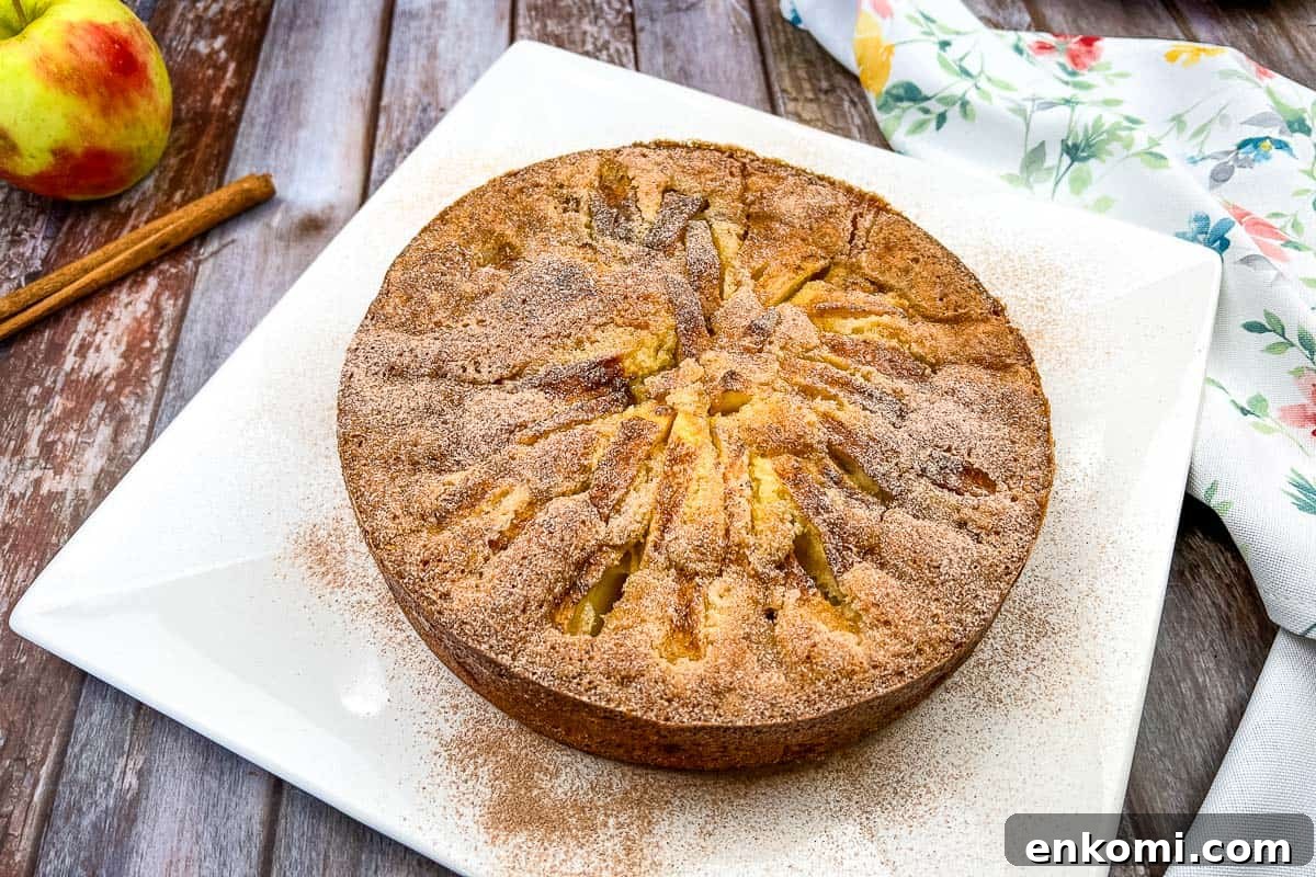 29 Fall Desserts That Bring Generations of Flavor Together 13 An apple cake on a white plate with cinnamon sticks.