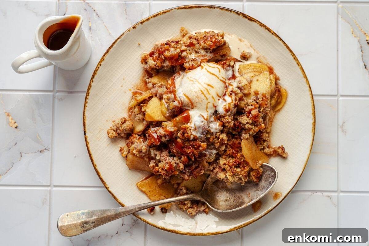 29 Fall Desserts That Bring Generations of Flavor Together 3 A plate of Classic Apple Crisp with a scoop of vanilla ice cream, served with a spoon.