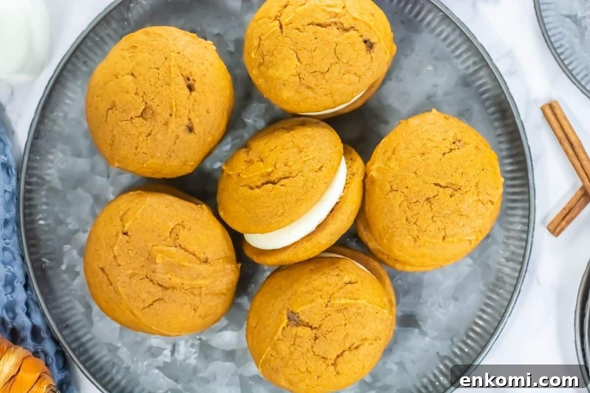 29 Fall Desserts That Bring Generations of Flavor Together 21 Six pumpkin whoopie pies with cream filling are arranged on a gray plate, viewed from above.