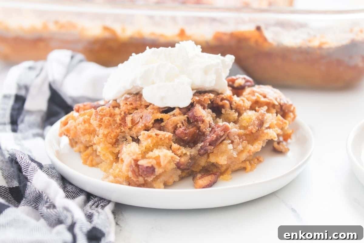 29 Fall Desserts That Bring Generations of Flavor Together 24 A slice of Pumpkin Crunch Cake on a white plate, topped with whipped cream.