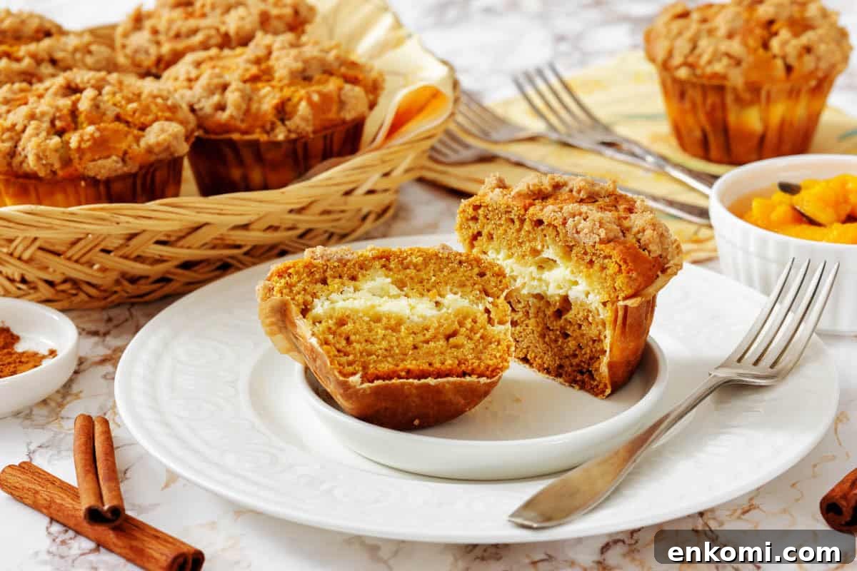 29 Fall Desserts That Bring Generations of Flavor Together 6 A Pumpkin Cream Cheese Muffin cut in half on a plate reveals a creamy filling.