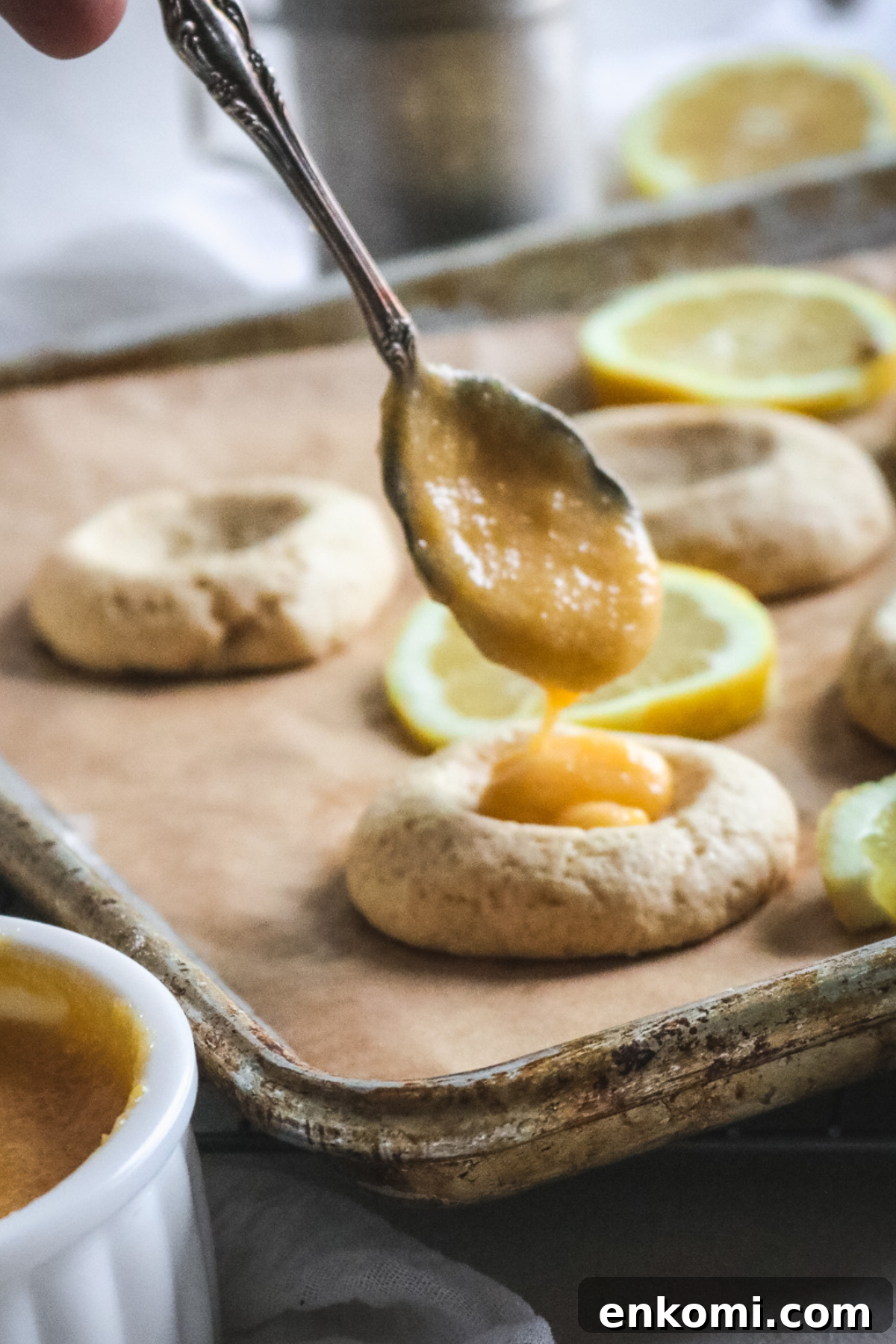 spooning lemon curd into freshly baked vanilla cookies to make lemon curd cookies.