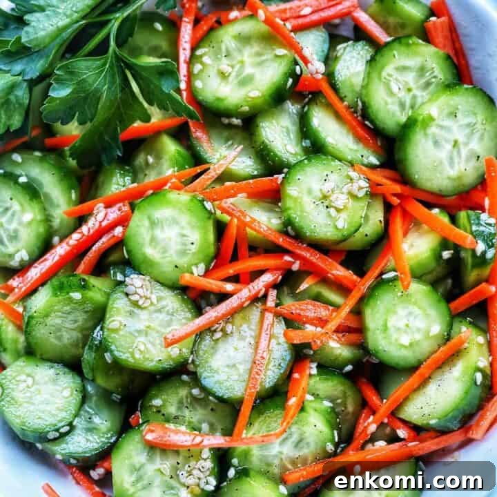 Bowl of sliced cucumbers, julienned carrots, sesame seeds, and herbs on the side.