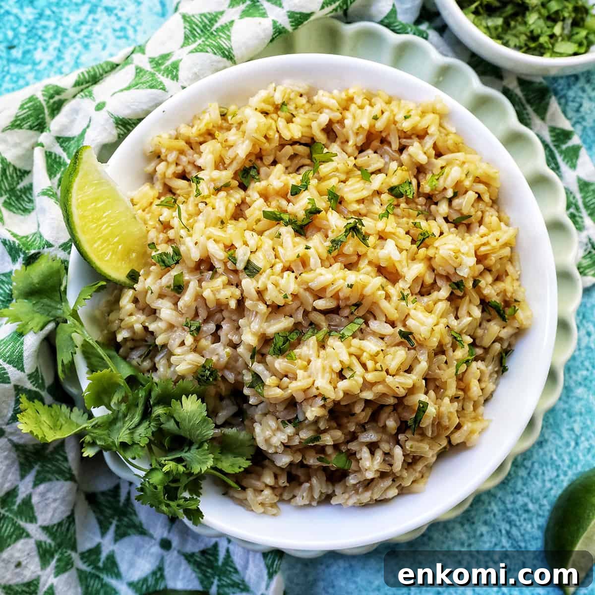 white bowl with Instant Pot Cilantro Lime Brown Rice on a green and white napkin with sides of cilantro leaves and lime wedges.