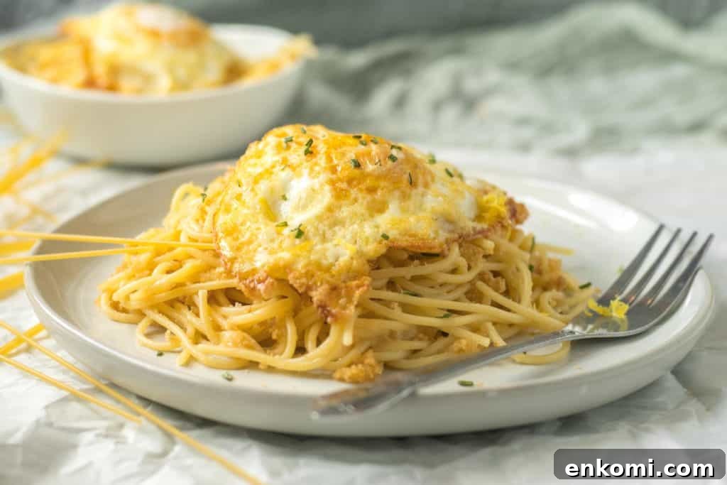 pasta pangrattato on a white plate with a fried egg on top with a fork next to it