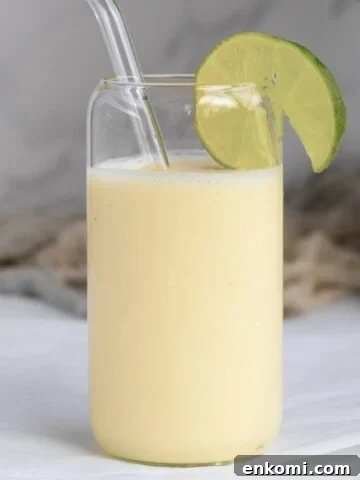 pina colada smoothie with a lime wedge in a glass
