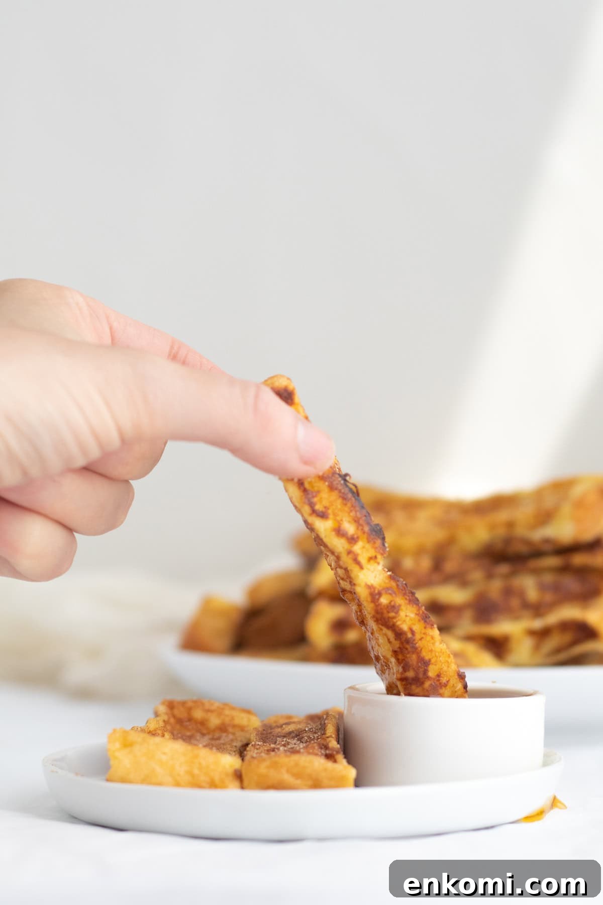 french toast sticks being dipped into maple syrup