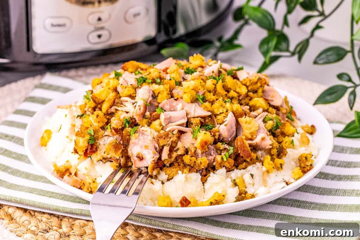 a plate of cut up crock pot pork chops and stuffing on top of mashed potatoes. 