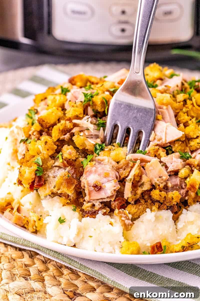 a fork inside pork and stuffing from the slow cooker on top of mashed potatoes. 