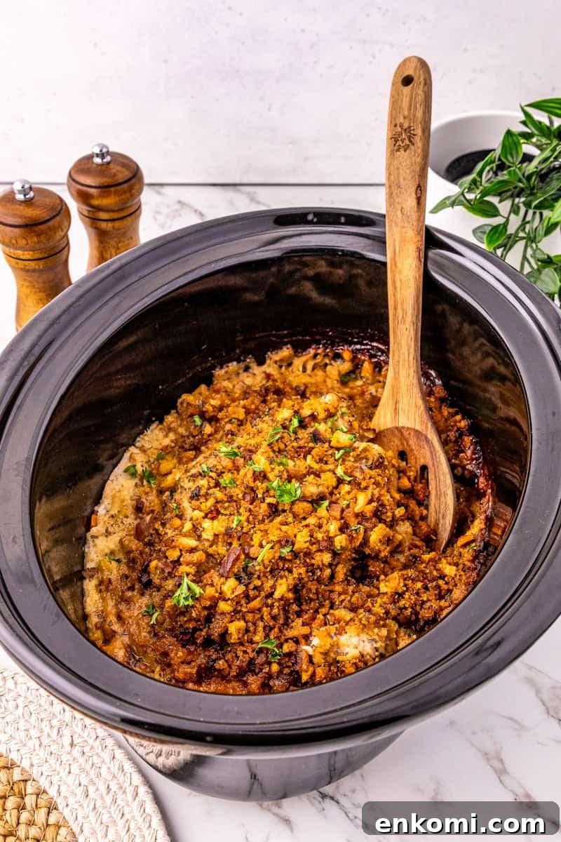 a black slow cooker with pork chops topped with stuffing.
