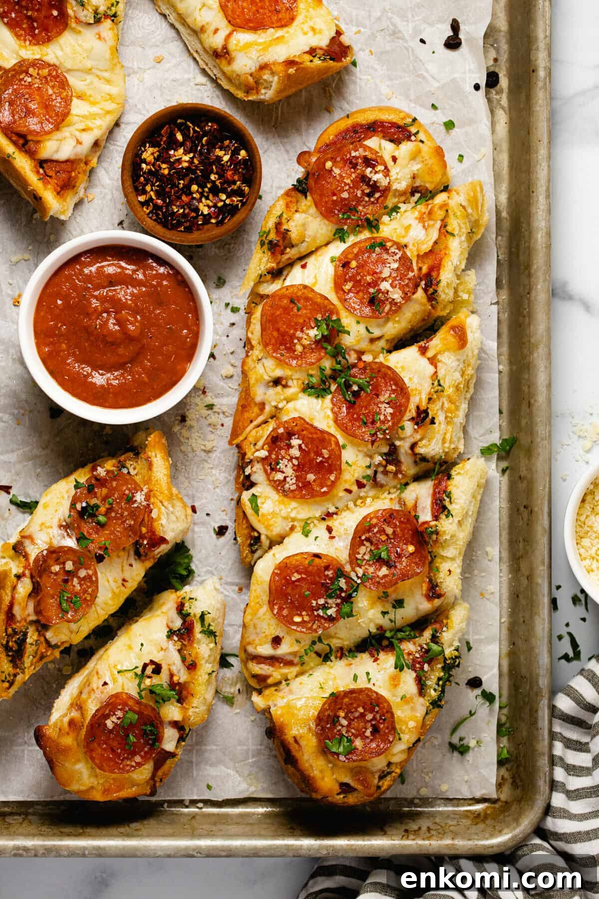 Baking sheet with homemade garlic bread pizza and a small bowl of pizza sauce
