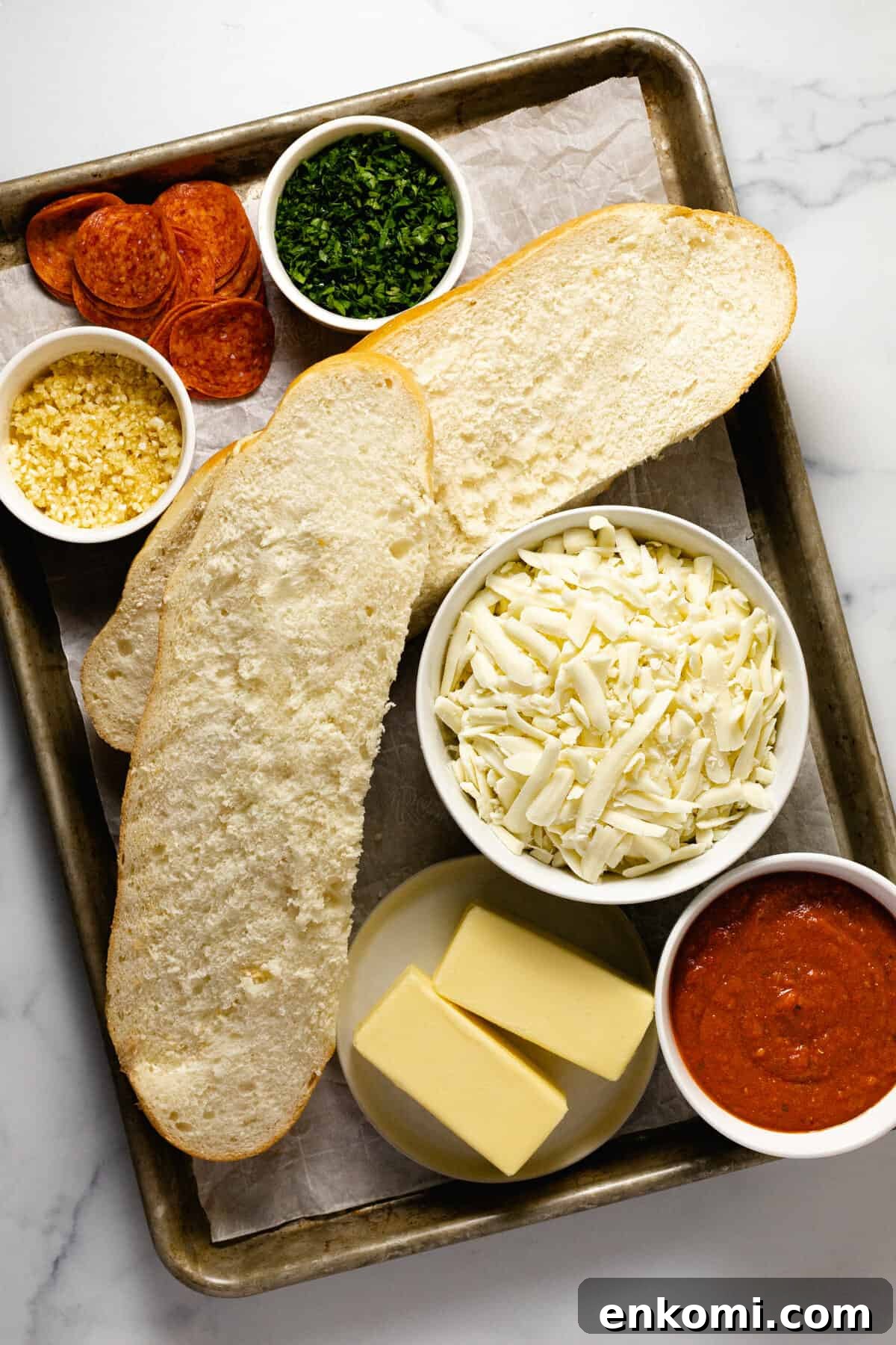 White marble counter top with ingredients to make homemade garlic bread pizza