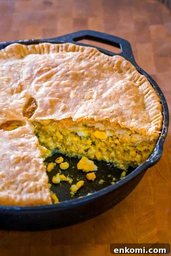 A corn pie, with a sliced remove, the filling of corn, egg, celery, onion, parsley can be seen inside.