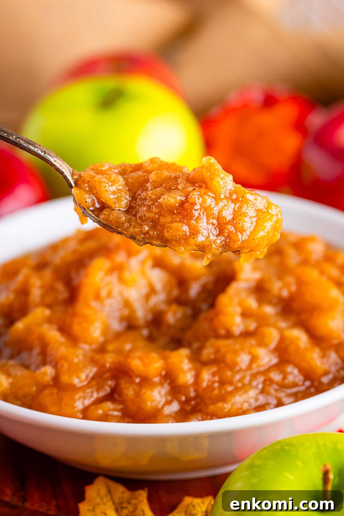 a spoon holding up a portion of homemade crock pot applesauce in air