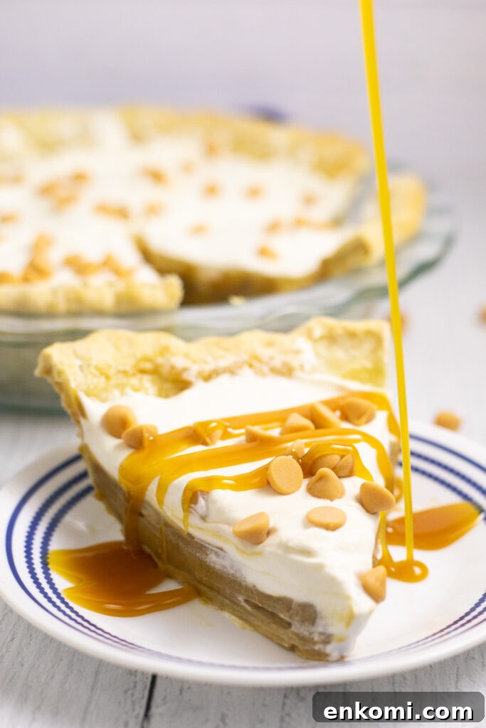 Classic Butterscotch Pie Recipe with Creamy Caramel Filling 3 Butterscotch sauce being drizzled onto homemade butterscotch pie on a small white plate with a rustic white wood background.