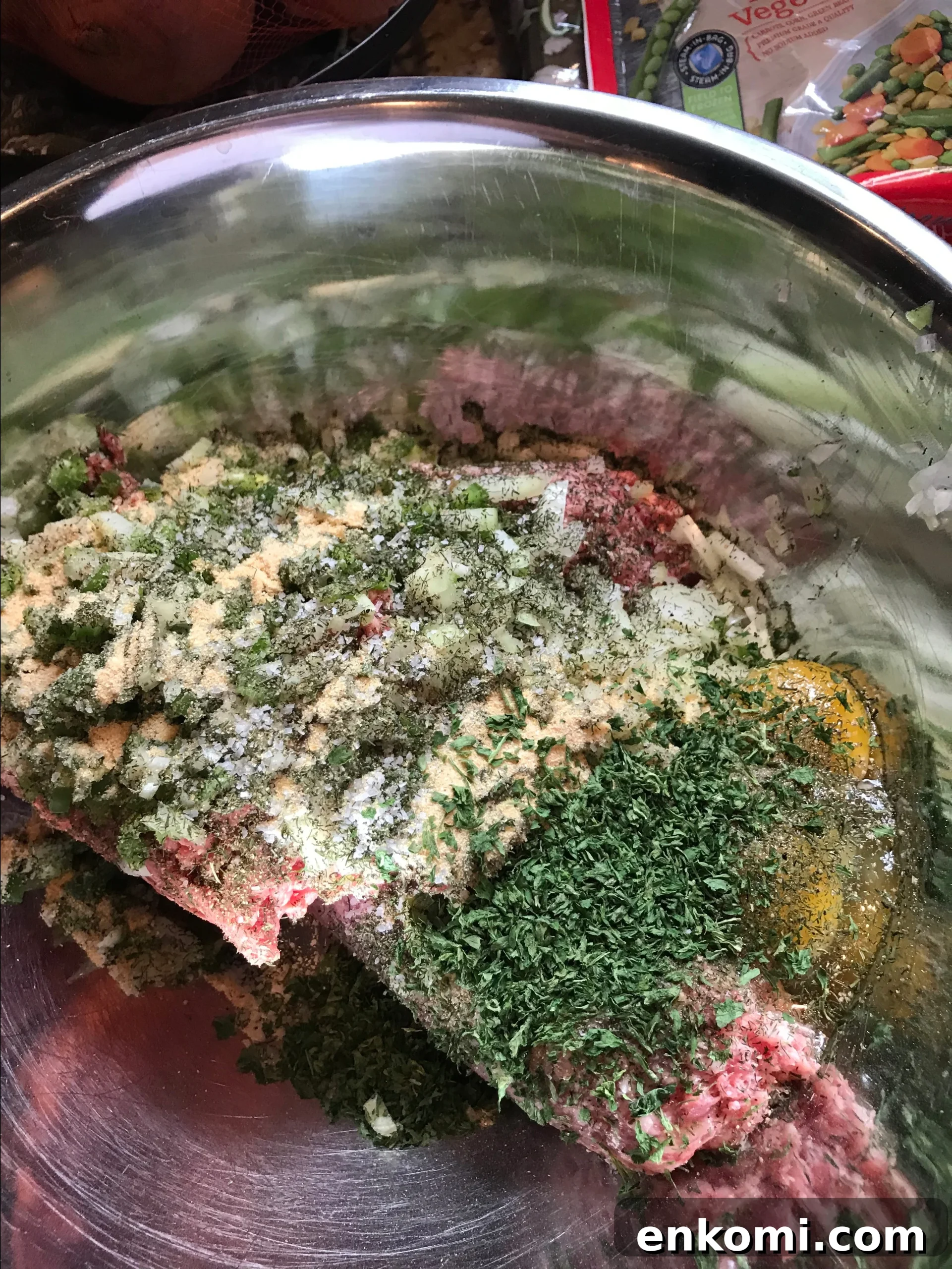 Ground meat, seasonings, and eggs in a metal bowl