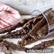 Homemade venison jerky in a glass that is on its side.