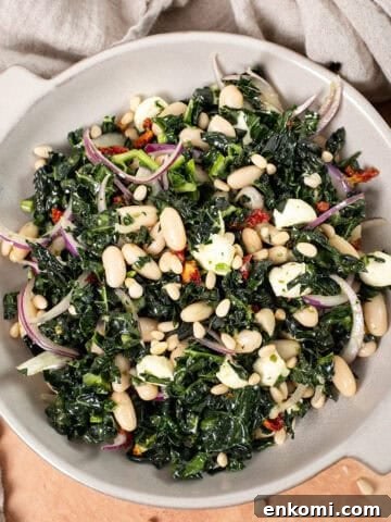 Kale and Cannellini Bean salad in a bowl topped with pine nuts.