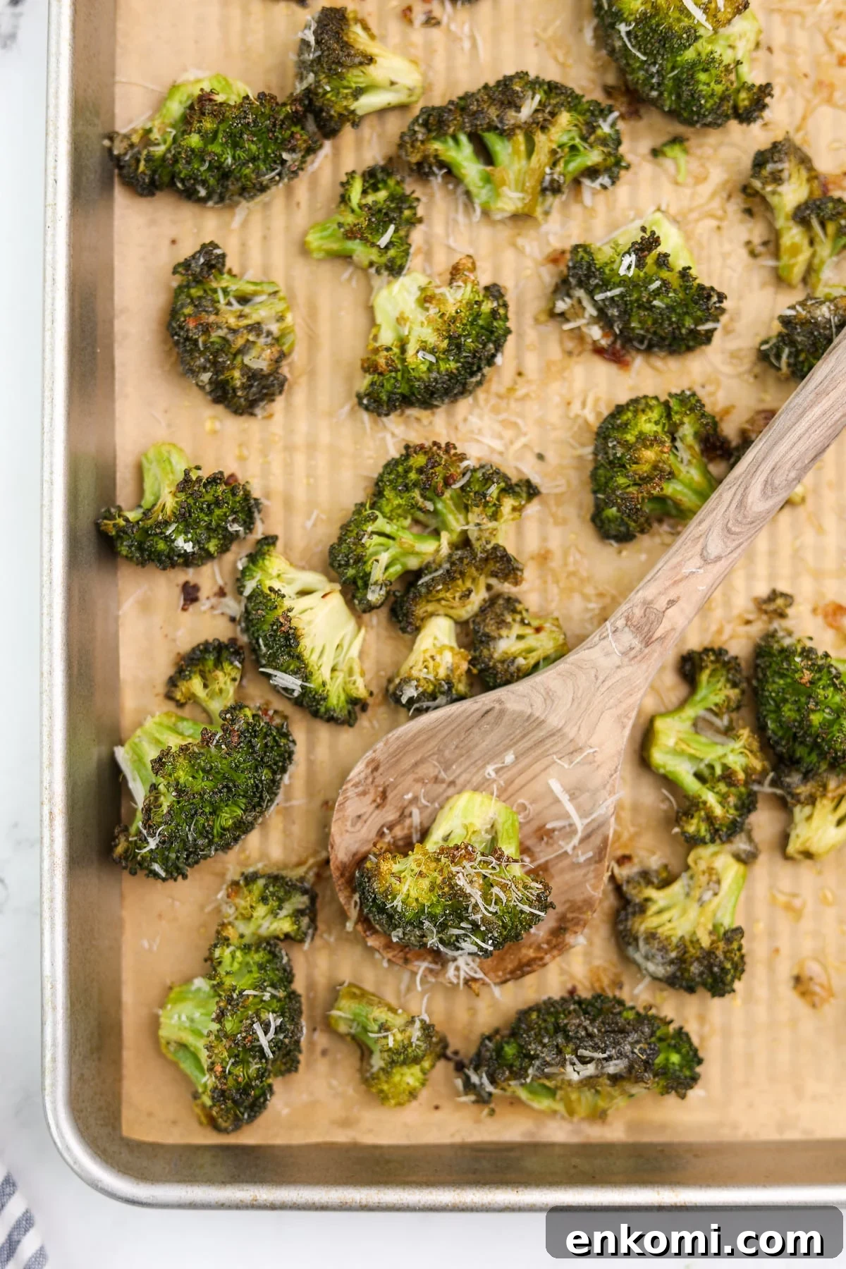 A baking sheet with roasted broccoli florets topped with parmesan cheese.