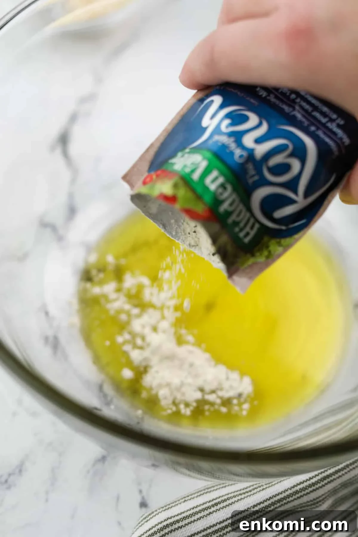 Sprinkling ranch seasoning into olive oil.