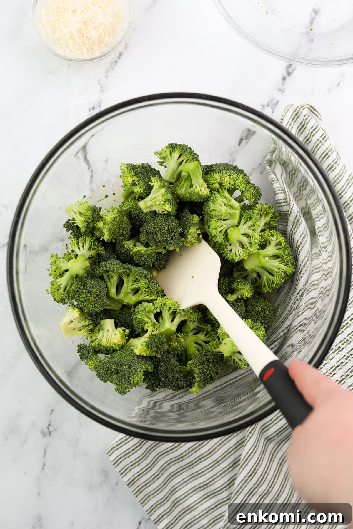 Stirring broccoli into a seasoned oil.
