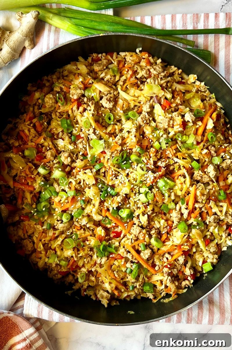 One-Pan Egg Roll Bowls with Ground Pork and Cabbage 7 One-pan egg roll bowls cooked in pan and topped with green onion slices and sesame seeds.