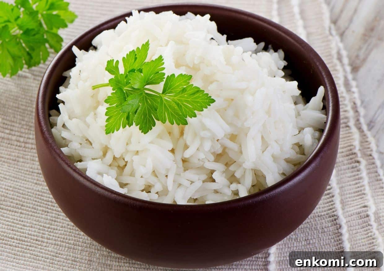 A bowl of white rice garnished with a sprig of parsley on a cloth surface.