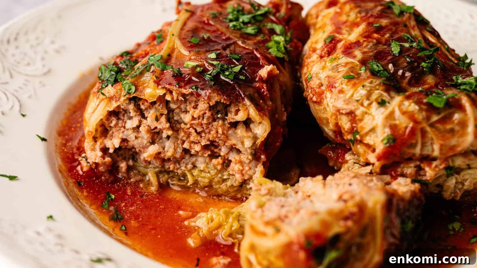 31 Spring Dinners That Feel Fresh, Not Fussy 14 Two cabbage rolls filled with ground meat and rice, topped with tomato sauce and chopped herbs, served on a white plate.