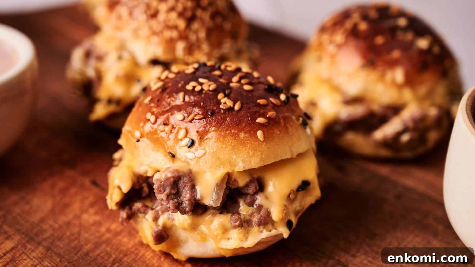 31 Spring Dinners That Feel Fresh, Not Fussy 18 Three sesame seed buns filled with melted cheese and ground beef are arranged on a wooden board.