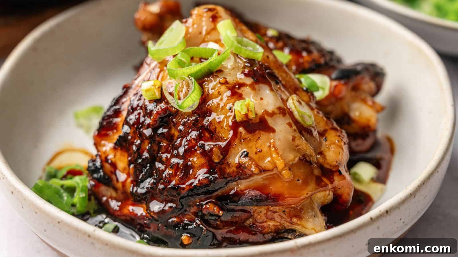 31 Spring Dinners That Feel Fresh, Not Fussy 19 A cooked chicken thigh glazed with a dark sauce, garnished with sliced green onions, served in a light-colored bowl.