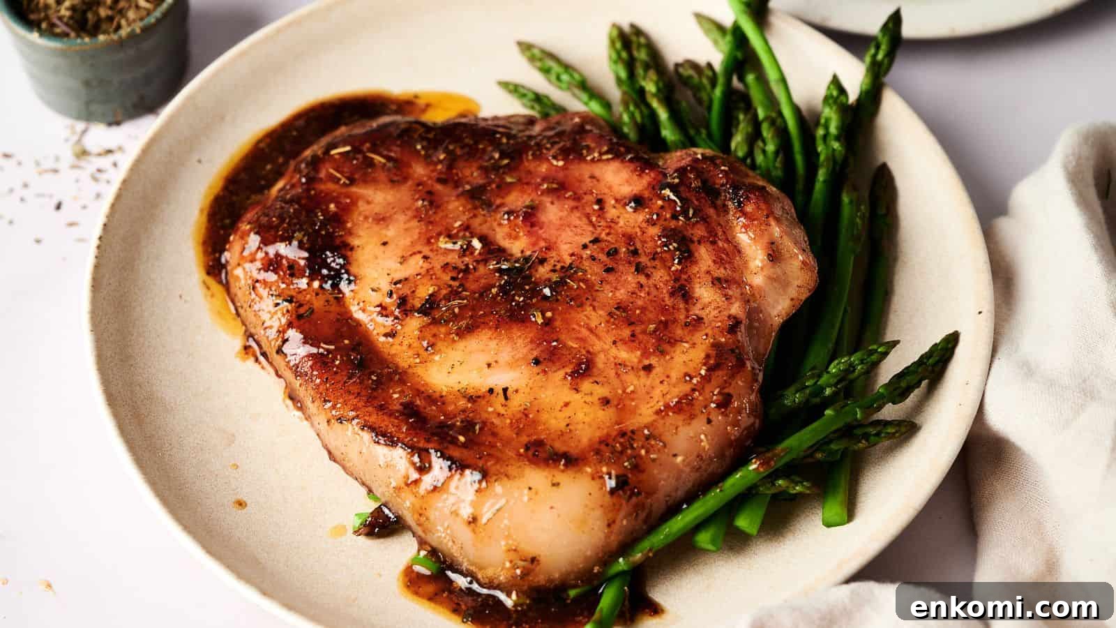 31 Spring Dinners That Feel Fresh, Not Fussy 20 A cooked pork chop with brown sauce is served on a white plate alongside steamed asparagus spears.