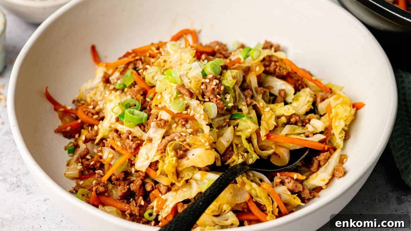 31 Spring Dinners That Feel Fresh, Not Fussy 3 A bowl of stir-fried ground meat, shredded cabbage, and carrots, topped with sesame seeds and chopped green onions.