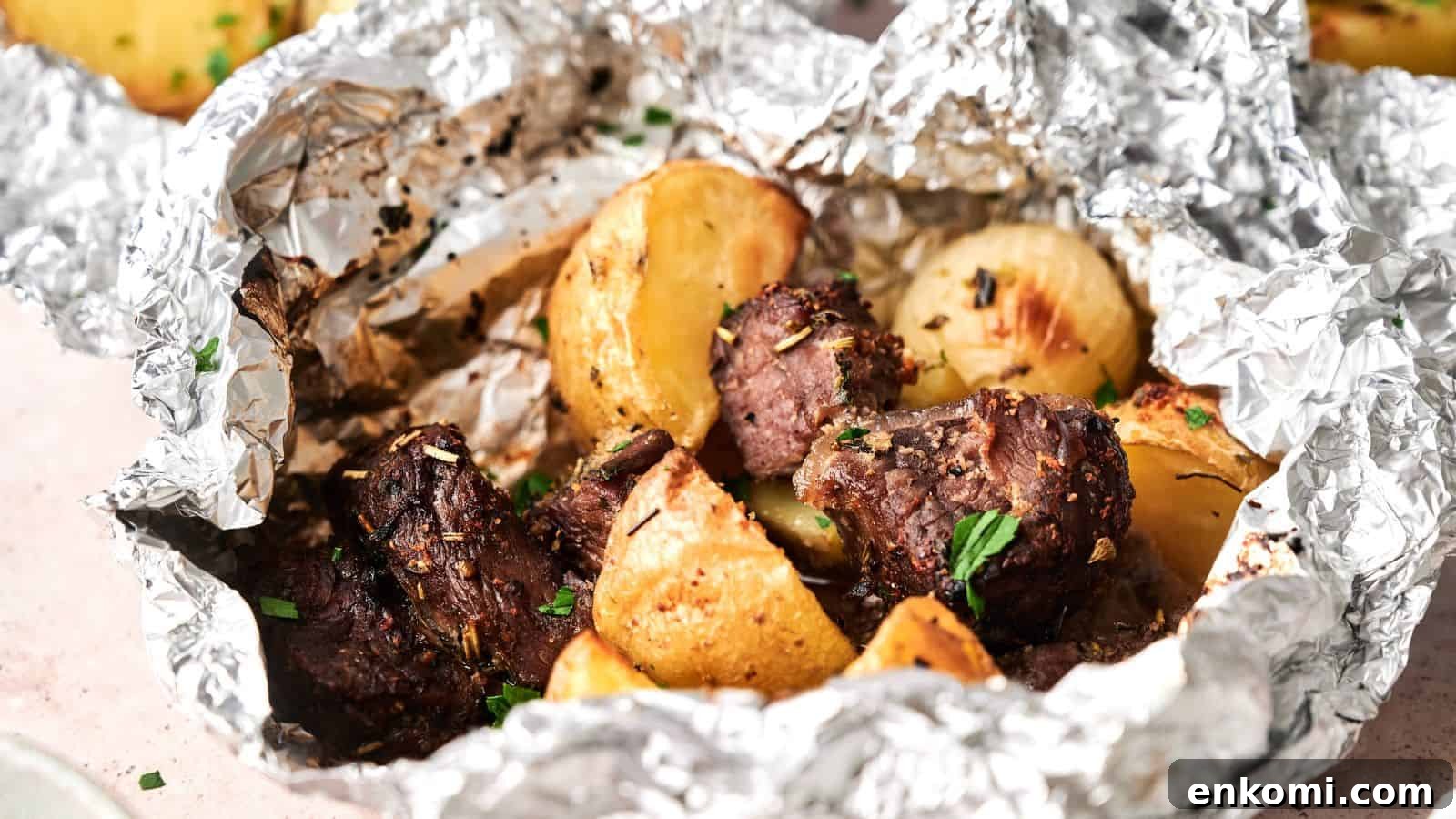 31 Spring Dinners That Feel Fresh, Not Fussy 22 Chunks of cooked beef and roasted potatoes served in an open aluminum foil packet, garnished with herbs.