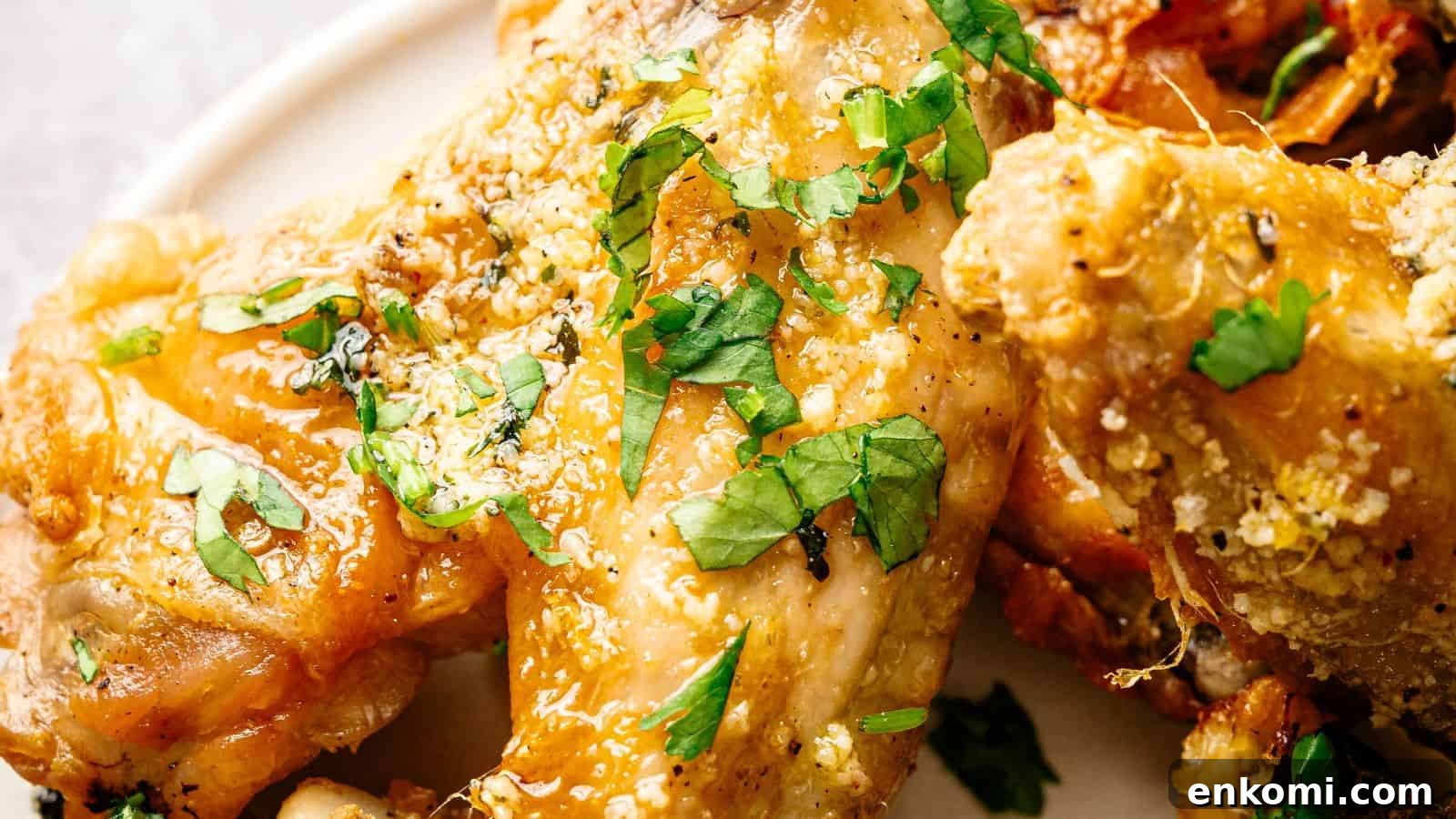 31 Spring Dinners That Feel Fresh, Not Fussy 23 Close-up of seasoned baked chicken wings garnished with chopped fresh parsley on a white plate.