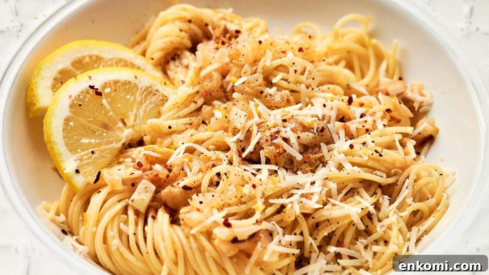 31 Spring Dinners That Feel Fresh, Not Fussy 27 A bowl of pasta with lemon slices and parmesan cheese.