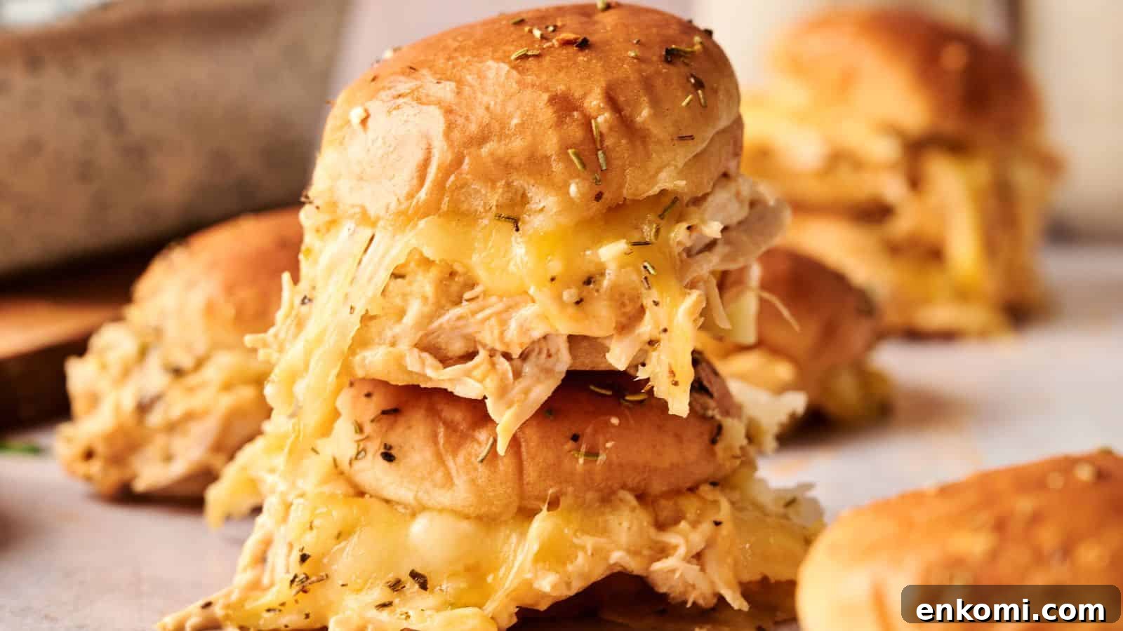 31 Spring Dinners That Feel Fresh, Not Fussy 4 A stack of slider sandwiches filled with shredded chicken and melted cheese, topped with herbs, on a light surface.