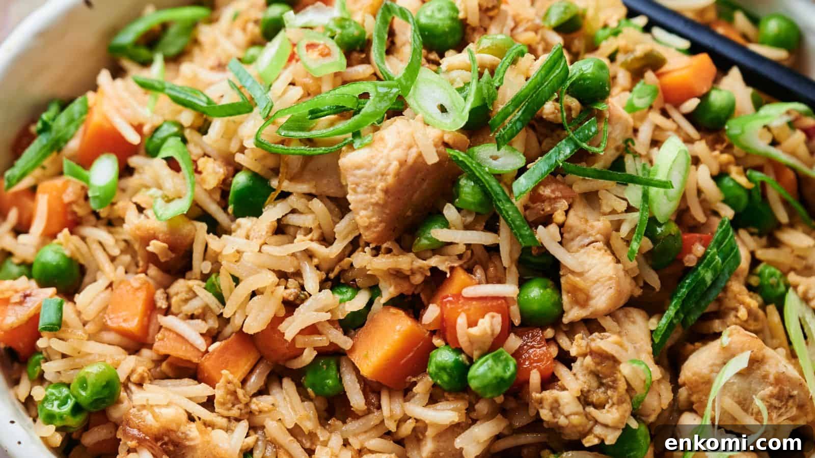 31 Spring Dinners That Feel Fresh, Not Fussy 31 Close-up of chicken fried rice with peas, carrots, sliced green onions, and chopsticks.