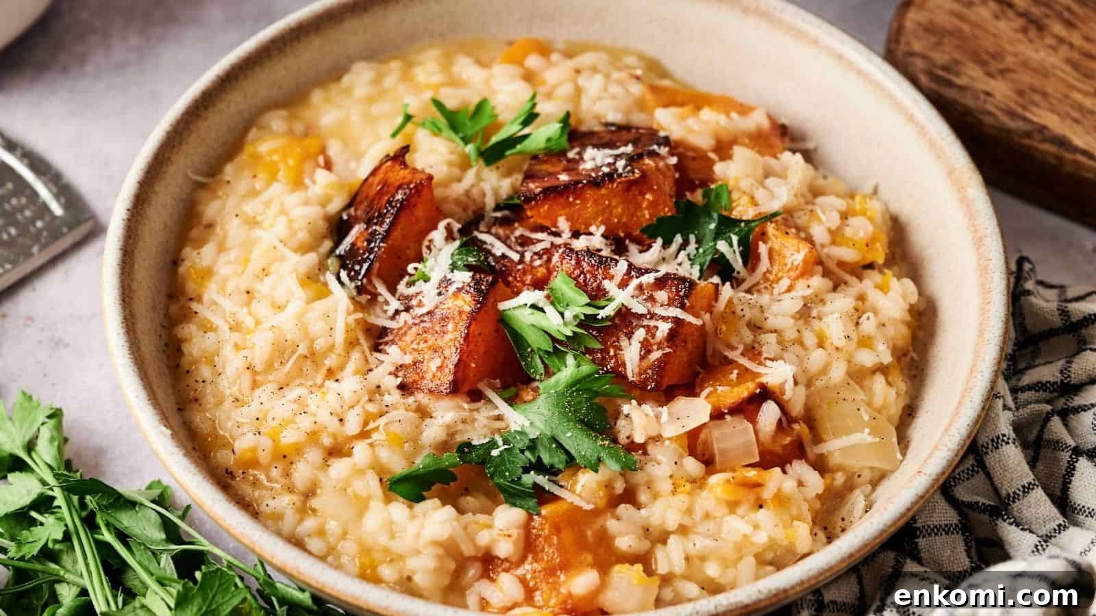 31 Spring Dinners That Feel Fresh, Not Fussy 32 A bowl of risotto topped with roasted pumpkin pieces, grated cheese, and fresh parsley, with a checkered napkin and herbs nearby.