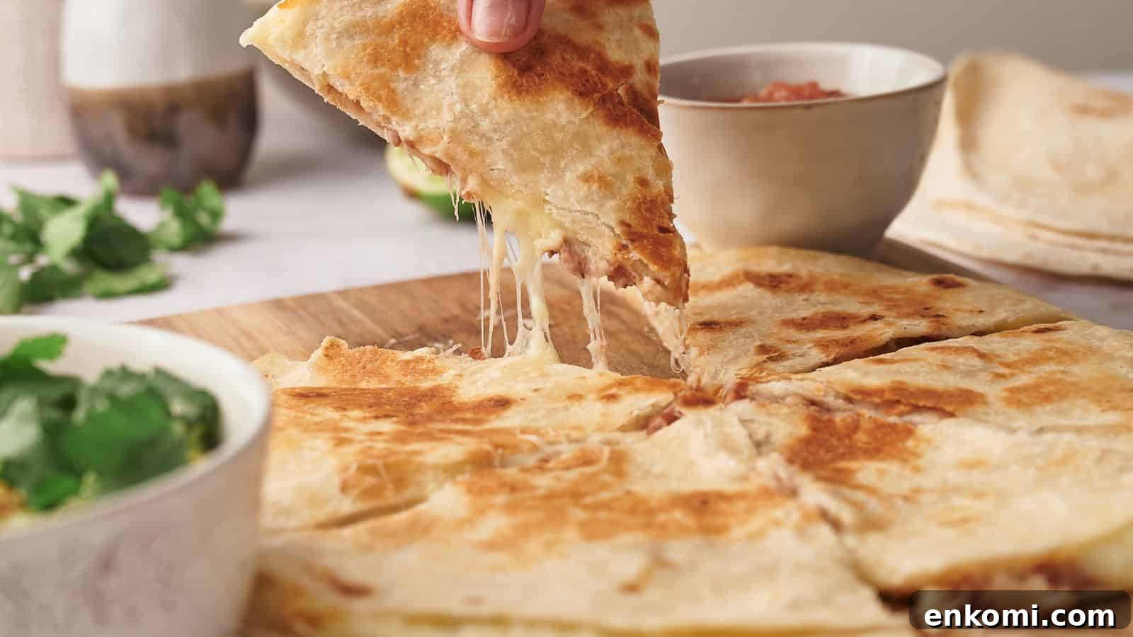 31 Spring Dinners That Feel Fresh, Not Fussy 7 A person lifts a cheesy quesadilla slice from a wooden board. Nearby are bowls of guacamole and salsa on a light-colored table.