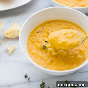 bowl of corn soup in white bowl with spoon taking bite