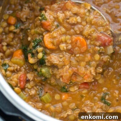 close up of sausage lentil soup being scooped with ladle