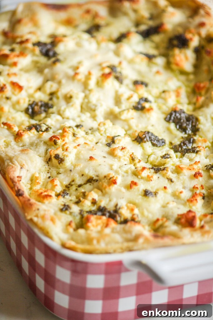 Roasted zucchini and pesto lasagna layered with cream cheese sauce and topped with feta