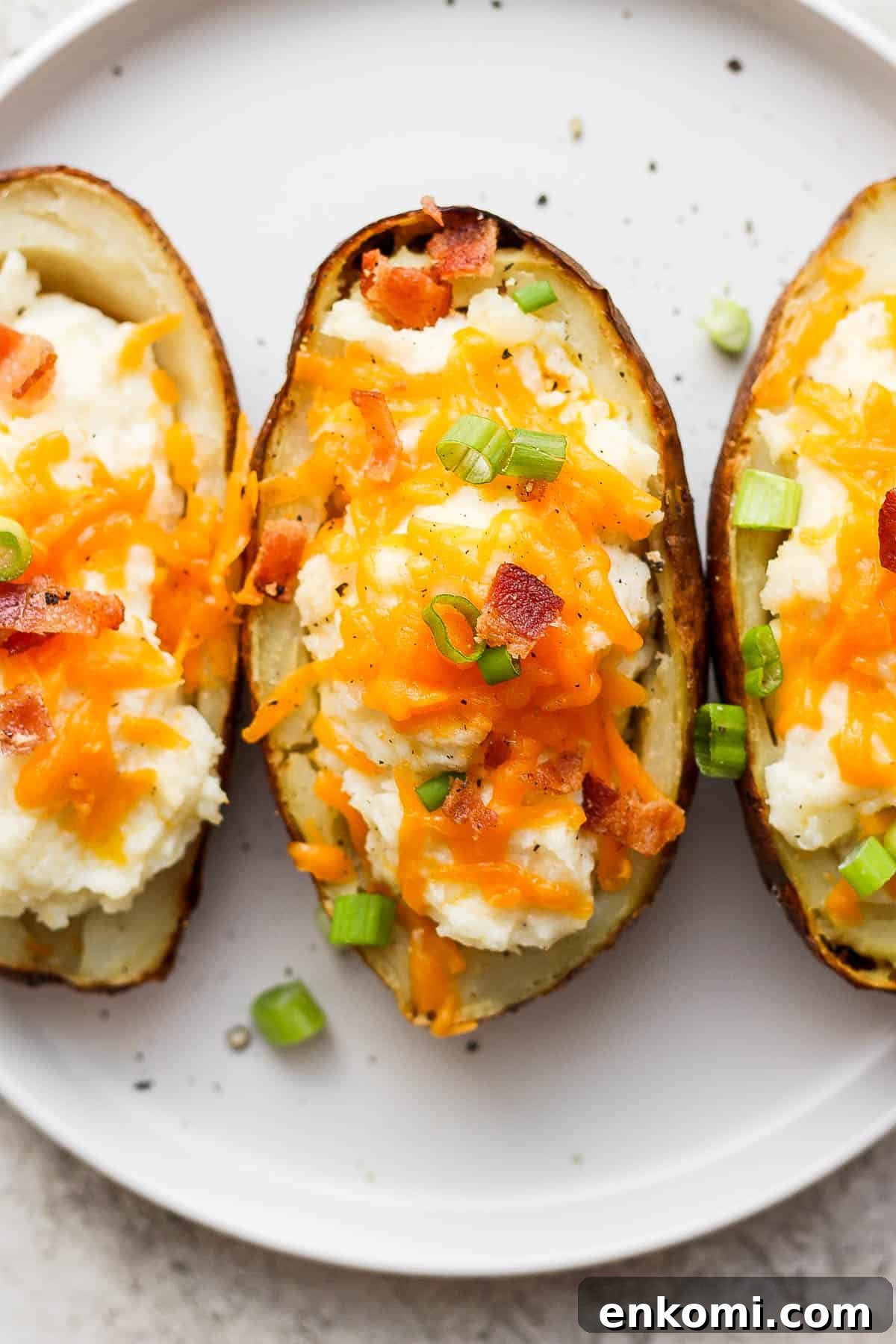 Twice-Baked Potatoes with Cheddar and Crispy Bacon 8 Twice baked potatoes on a white plate.
